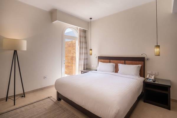 Schlafzimmer im Fort Arabesque Resort, Spa & Villas mit einem großen Bett, zwei weißen Kissen und einer Lampe.