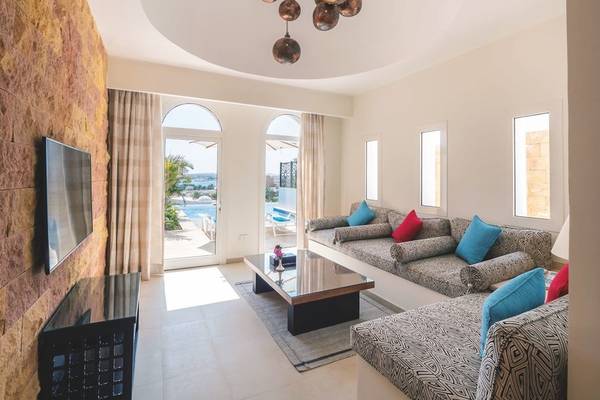 Innenansicht des Wohnzimmers im Fort Arabesque Resort mit Sofas, Tisch und Fernseher.