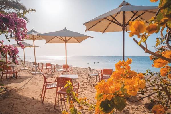 Außenbereich des Fort Arabesque Resorts mit Strand, Tischen, Stühlen und Sonnenschirmen