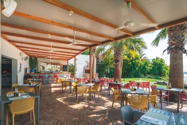 Terrasse des Fort Arabesque Resorts, Spa & Villas mit Tischen und Stühlen, Palmen und Blick auf den Strand