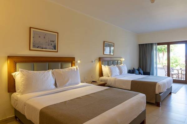 Schlafzimmer im Fort Arabesque Resort mit zwei Betten, Dekor und Balkonzugang.