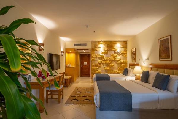Fort Arabesque Resort Doppelbett Zimmer mit steinerner Wand, Fernseher, Tisch und Stühlen.