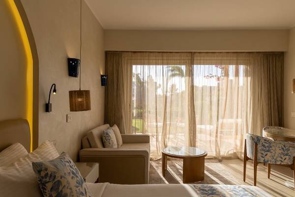 Zimmer im Fort Arabesque Resort, Spa & Villas mit großer Fensterfront und Gartenblick.