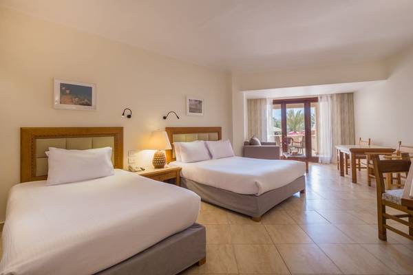 Schlafzimmer im Fort Arabesque Resort mit zwei Betten, Tisch und Fenster mit Blick auf den Garten