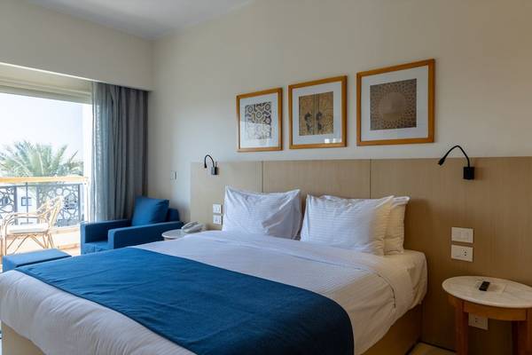 Schlafzimmer im Fort Arabesque Resort mit Bett, Nachttischen und Bildern an der Wand.
