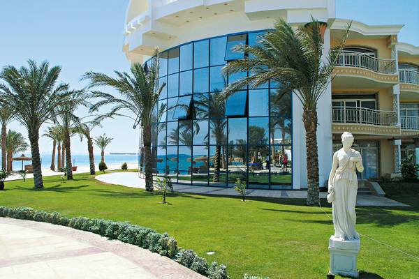 Außenansicht des Palm Royale Soma Bay Hotels mit Glasfassade und Statue im Vordergrund.