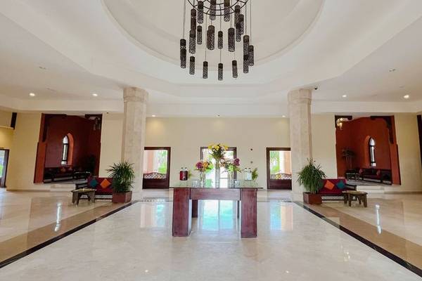 Lobbybereich des Gemma Resorts mit einer großen Holztisch, Blumen, hohen Decken und Kronleuchter