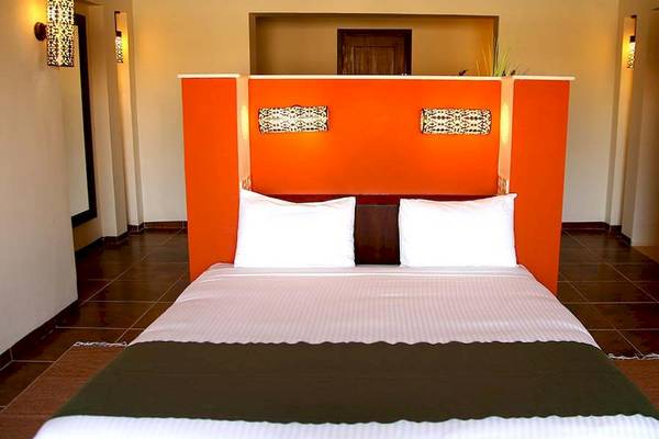 Ein Bett im Gemma Resort mit einem orangefarbenen Kopfteil und weißen Kissen.