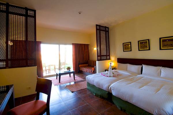 Doppelzimmer im Gemma Resort mit zwei Betten, Terrassenblick und Wohnzimmerbereich.