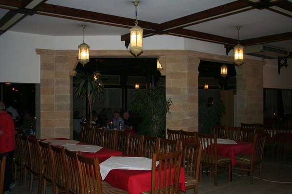 Innenbereich des Mangrove Bay Resorts mit gepolsterten Stühlen und Tischen, roten Tischdecken und hängenden Lampen.