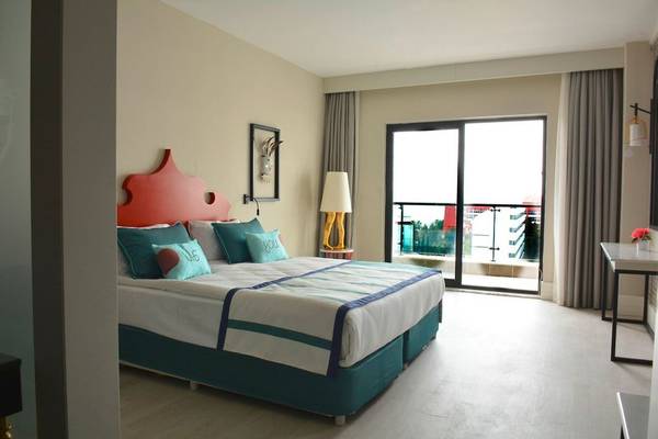 Schlafzimmer im Seaden Valentine Resort & Spa mit einem Doppelbett, Fenstern und Balkon.