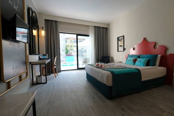 Innenansicht eines Zimmers im Seaden Valentine Resort & Spa mit Bett, Schreibtisch und Terrassenzugang.