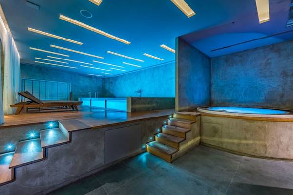 Innenbereich des Badezimmers im Alexandra Beach Resort mit beleuchteten Stufen und Whirlpool.