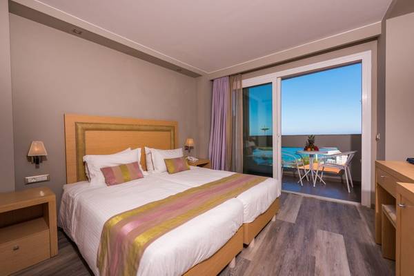 Doppelbett Zimmer mit Balkon im Alexandra Beach Resort mit Blick auf den Pool.