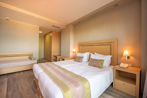 Doppelzimmer im Alexandra Beach Resort mit zwei Betten, Nachttischen und Lampen.