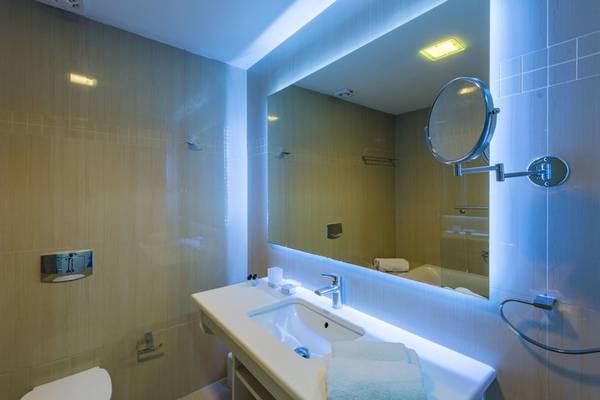 Badezimmer im Alexandra Beach Resort mit Spiegel, Waschbecken und Badewanne.
