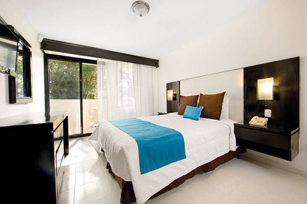 Schlafzimmer im Viva Dominicus Beach Hotel mit einem großen Bett, dunklen Möbeln und einer Terrassentür.