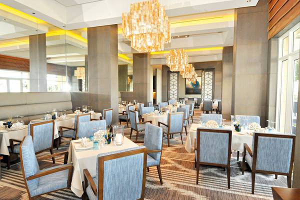 Innenansicht des Restaurants im Barcelo Mussanah Resort mit blauen Stühlen und weißen Tischen.