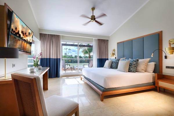 Schlafzimmer im Grand Palladium Punta Cana Resort & Spa mit einem großen Bett, Fernseher, und Blick auf die Terrasse