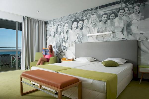 Doppelzimmer mit Meerblick und Wandbild von Bademode im Excelsior Hotel.