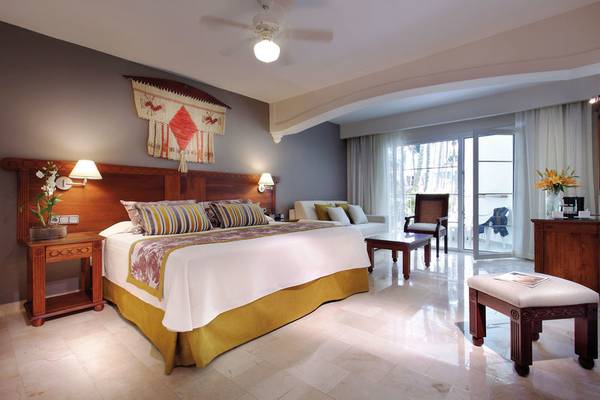 Schlafzimmer im Grand Palladium Punta Cana Resort & Spa mit Doppelbett, Nachttischen, Lampen und einem Wohnzimmerbereich.