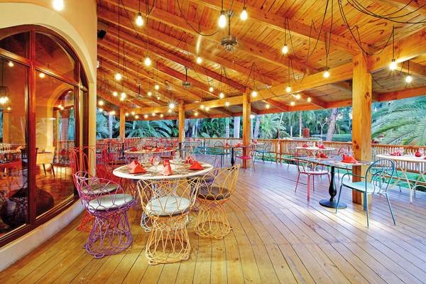 Terrasse des Grand Palladium Punta Cana Resorts & Spa mit bunten Stühlen und Tischen.