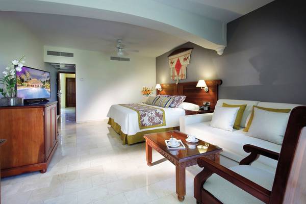 Suite-Zimmer im Grand Palladium Punta Cana Resort & Spa mit Bett, Fernseher und Wohnzimmerbereich.