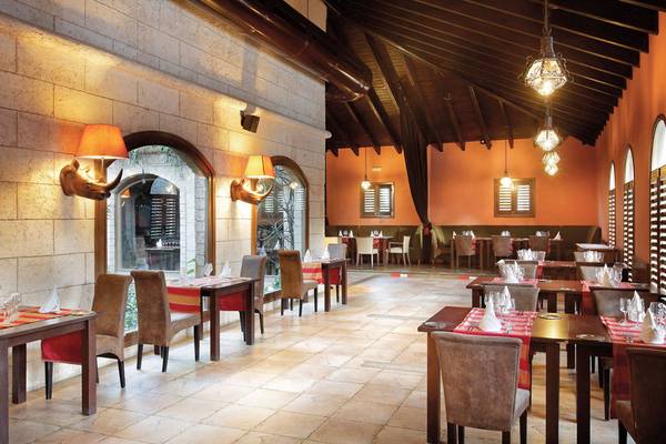 Innenansicht des Restaurants im Grand Palladium Punta Cana Resort & Spa mit gefliesten Böden und Holztischen.