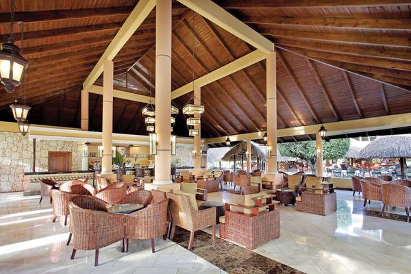 Innenbereich des Grand Palladium Punta Cana Resort & Spa mit Holzdecken, Rattanmöbeln und hängenden Lampen.