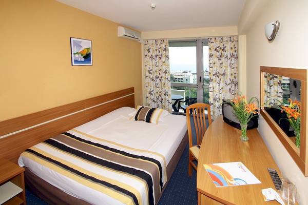 Excelsior Hotel Zimmer mit Bett, Schreibtisch und Aussicht auf die Stadt.