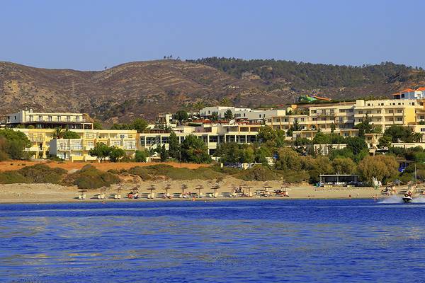 Blick auf das LABRANDA Kiotari Miraluna Resort mit vielen Gebäuden und Bäumen im Hintergrund und einer Person auf einem Wasserscooter im Vordergrund.