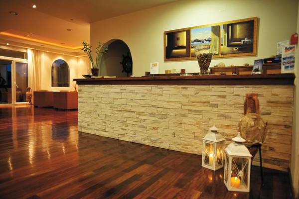 Rezeption des Naftilos Boutique Hotel mit Steinwand, zwei Laternen und einem Gemälde