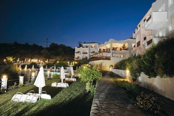Nachtansicht des Naftilos Boutique Hotels mit beleuchteten Wegen, Liegestühlen und Swimmingpool.