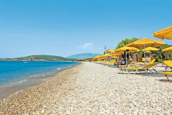 Strand des Saint Nicholas Hotel Samos mit gelben Sonnenschirmen und Liegen
