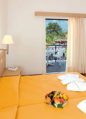 Zimmer im Saint Nicholas Hotel Samos mit Balkon und Obstteller auf dem Bett.