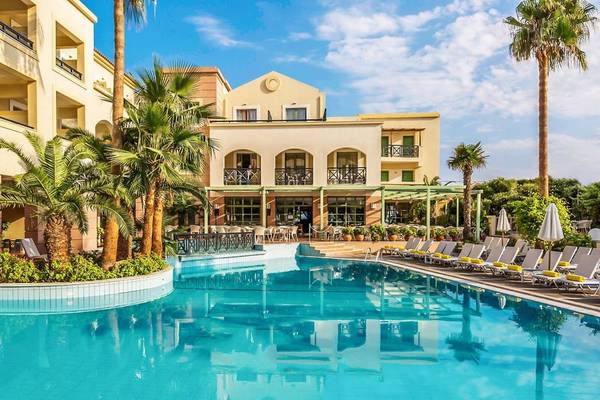 Außenbereich des Samaina Inn Hotels mit Swimmingpool, Palmen und Sonnenliegen.