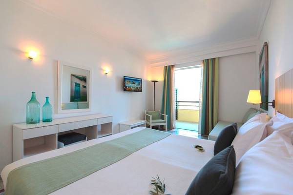 Hotelzimmer im Samaina Inn mit Bett, Fernseher und Balkon.