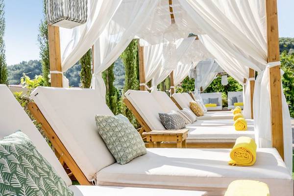 Reihe von weißen Lounge-Sesseln mit gelben Handtüchern unter einem weißen Vordach im Freien, Samaina Inn.