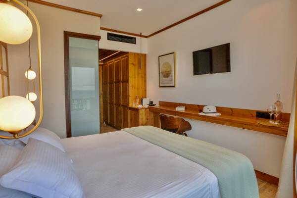 Schlafzimmer im Sunrise Hotel Samos mit Bett, Lampen und Fernseher an der Wand.