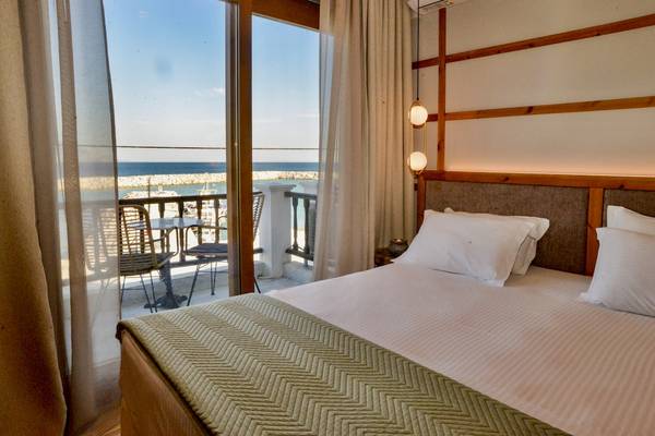 Ein modernes Hotelzimmer mit Meerblick im Sunrise Hotel Samos, inklusive eines Bettes, eines Balkons und eines Tisches.