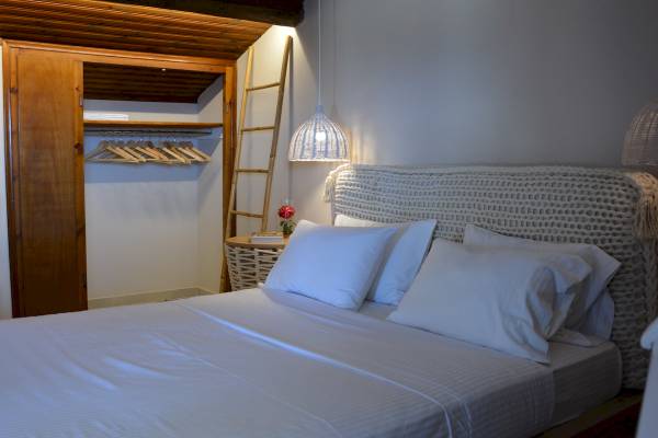 Schlafzimmer im Sunrise Hotel Samos mit Bett, Kleiderschrank und Deko-Elementen.