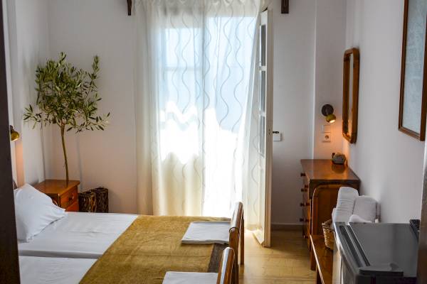 Doppelzimmer mit zwei Betten, einer offenen Tür und einem Fenster mit Vorhängen.