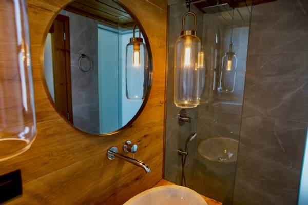 Badezimmer mit einem runden Spiegel und zwei Glaslampen an der Wand.
