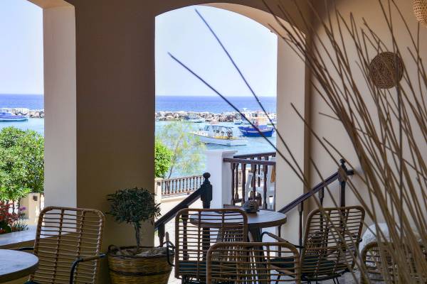 Terrasse mit Meerblick im Sunrise Hotel Samos, mit Tischen, Stühlen und einem kleinen Baum.