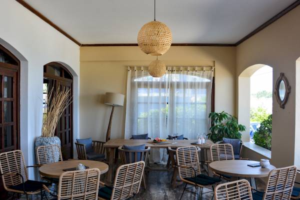 Innenbereich des Sunrise Hotel Samos mit runden Tischen und Stühlen, Lampen und Pflanzen.