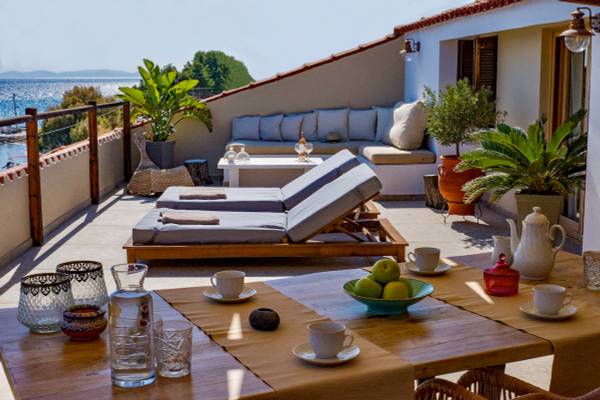 Terrasse des Sunrise Hotels Samos mit Loungemöbeln, Blick auf das Meer und Obstschalen auf dem Tisch.
