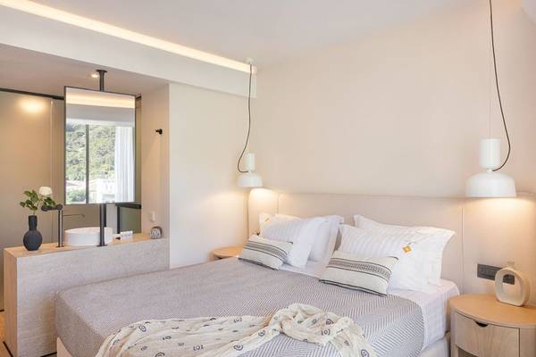 Schlafzimmer im Erato by Samian Mare Hotel mit weißem Bett und modernen Leuchten.