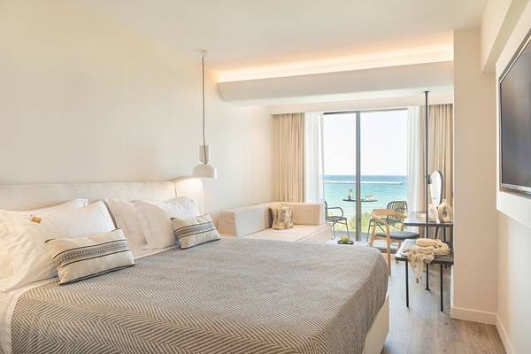 Schlafzimmer des Erato by Samian Mare Hotels mit Meerblick, Bett, Sofa und Tisch.