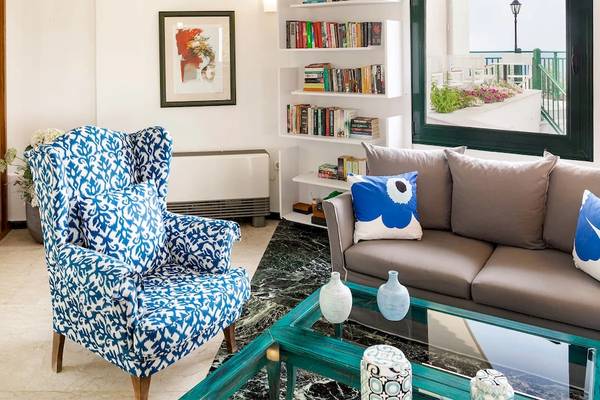 Wohnzimmer des Kalidon Panorama Hotels mit blauem Sessel, grauem Sofa und Bücherregal.