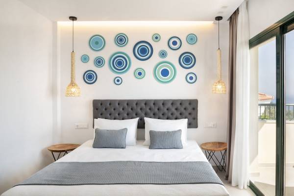 Schlafzimmer mit Bett, grauem Kopfteil und dekorativen blauen und grünen Kreisen an der Wand.